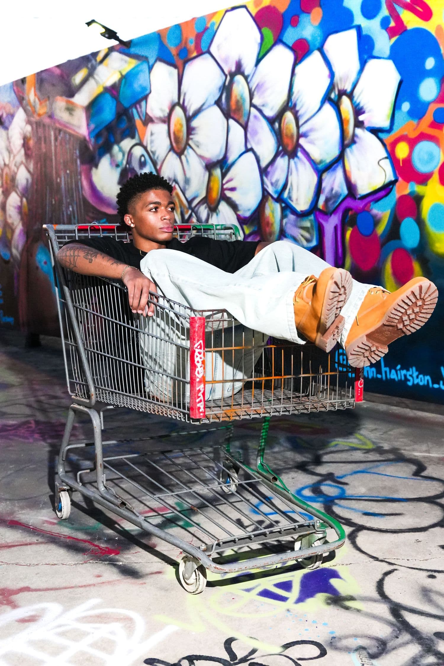 Lounging inside a shopping cart in front of a giant flower mural